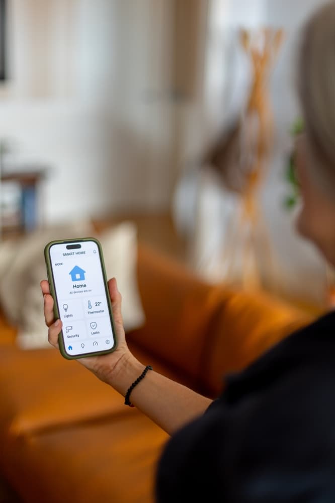 Smart Home : Application de domotique pour smartphone Application Smart Home sur smartphone contrôlant thermostat à 22°C, lumières et sécurité dans un salon moderne.