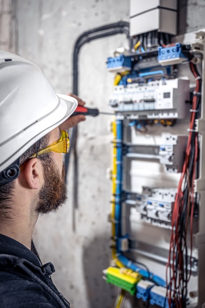 Installation tableau électrique par un électricien qualifié Électricien en équipement de sécurité installant des disjoncteurs dans un tableau électrique avec un tournevis.
