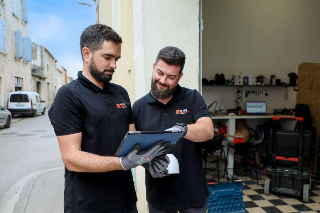 Techniciens Le Duc Énergies : Solutions et expertise terrain Techniciens Le Duc Énergies collaborant sur une tablette devant leur atelier.
